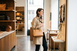 Femme élégante tenant un sac à main en cuir camel dans une boutique parisienne, illustrant comment choisir le bon sac selon son style